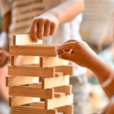 Children building a tower using the natural Kapla wooden construction planks 