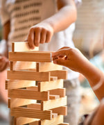 Children building a tower using the natural Kapla wooden construction planks 