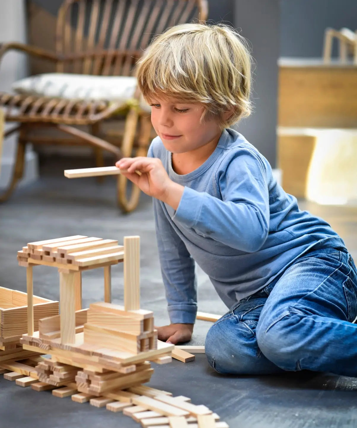 Child building a train made from the natural Kapla wooden construction planks 