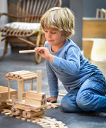 Child building a train made from the natural Kapla wooden construction planks 
