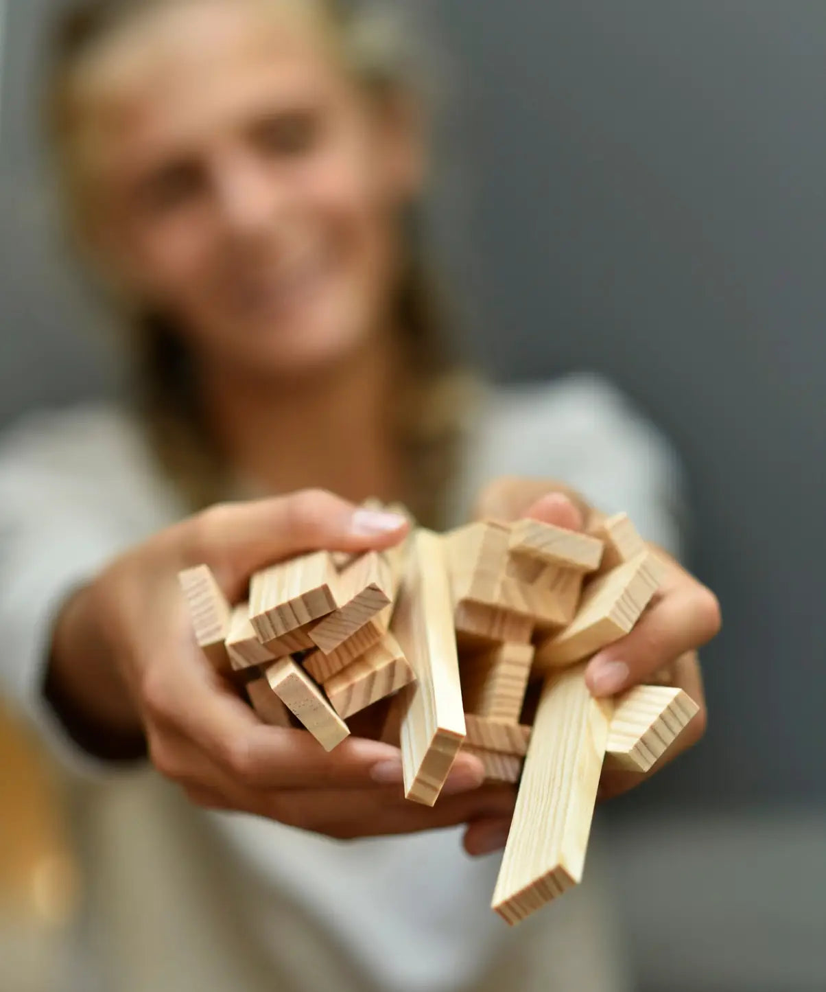 Adult holding a pile of Kapla unpainted natural wooden construction planks