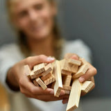 Adult holding a pile of Kapla unpainted natural wooden construction planks