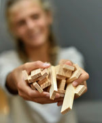 Adult holding a pile of Kapla unpainted natural wooden construction planks
