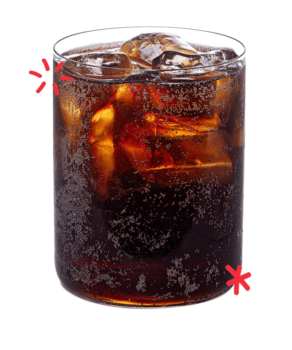 Glass of Karma Cola served over ice, showing the deep colour and natural fizz of this organic Fairtrade cola made with real kola nuts.