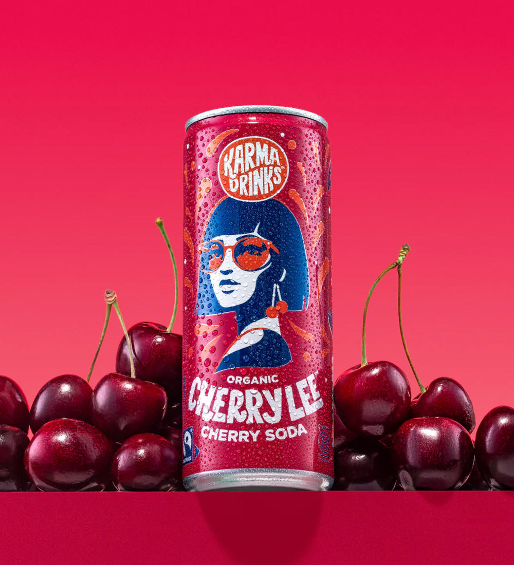 Can of Karma Drinks Cherry Lee organic cherry soda displayed with fresh cherries, showcasing its natural cherry flavour and Fairtrade certification.