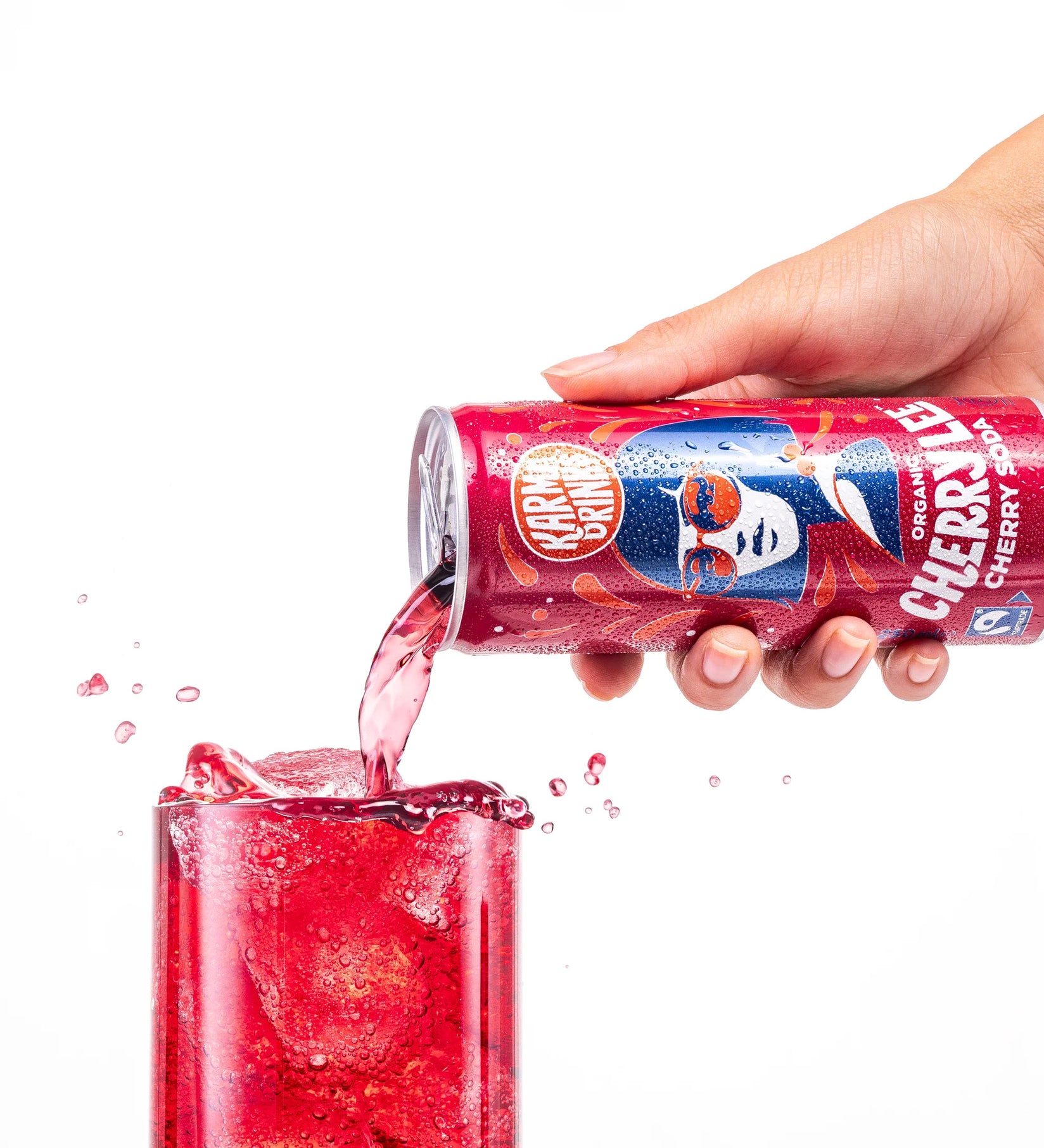 Karma Drinks Cherry Lee organic cherry soda being poured from the can into a glass of ice, highlighting the vibrant red colour and Fairtrade branding.