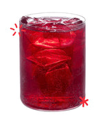 Bright red organic Cherry Lee cherry soda poured over ice, showing the colour and fizz of Karma Drinks’ Fairtrade cherryade.