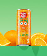 Karma Drinks Organic Orangeade can displayed with fresh oranges, highlighting the Fairtrade Valencia orange ingredients and vibrant citrus flavour.