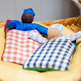 2 Kathe Kruse baby waldorf dolls lying inside gingham blankets on a wicker basket