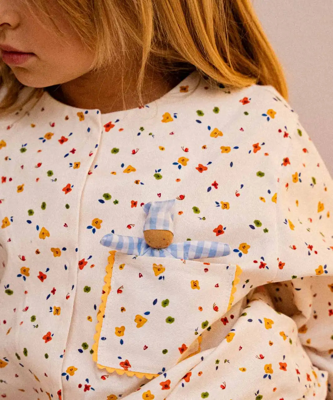 The doll from the Käthe Kruse soft toy baby with a blue check sleeping bag in a child's pocket. 