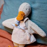 Käthe Kruse Eva duck standing soft toy wearing a white apron with red dots all over. There is a small doll in the apron pocket.