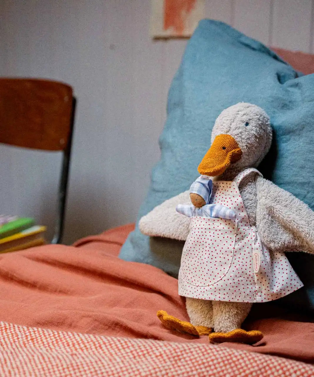 Käthe Kruse Eva duck standing soft toy wearing a white apron with red dots all over. 