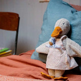 Käthe Kruse Eva duck standing soft toy wearing a white apron with red dots all over. 