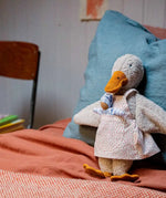 Käthe Kruse Eva duck standing soft toy wearing a white apron with red dots all over. 