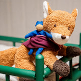 Käthe Kruse Finn fox lying soft toy placed in a green dolls cot. 