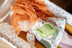 Käthe Kruse Waldorf doll Elsa laying in a dolls cot with the green felt snail that comes with her placed on her.