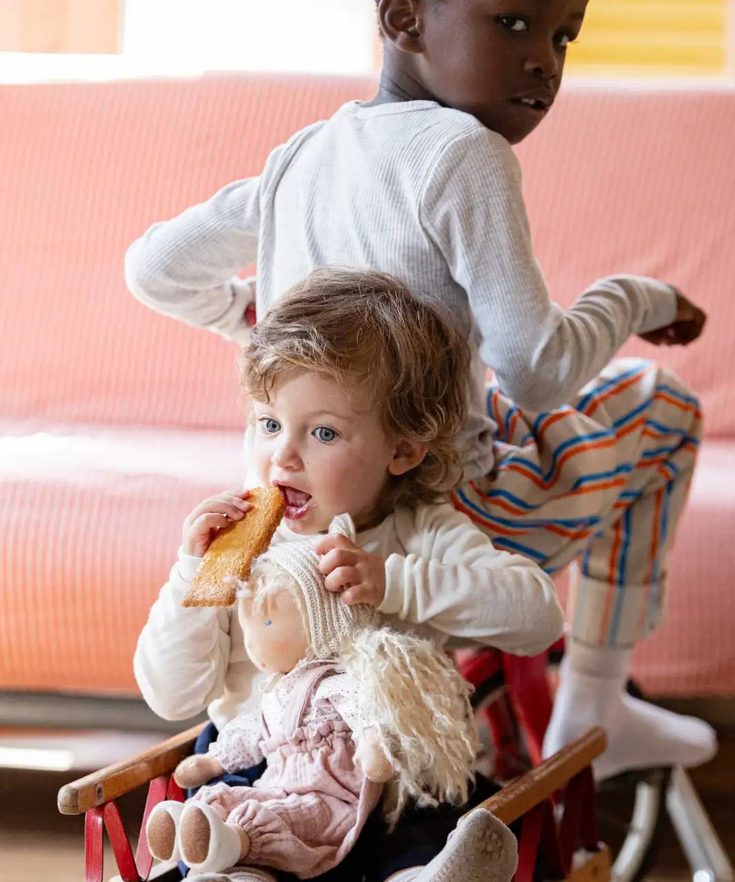 Child holding a Hannah Kathe Kruse waldorf doll and sitting in a trailer on a bike