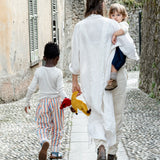 Mother carrying child with a saffron Kathe Kruse doll in hand and a child holding the doll