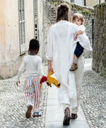 Mother carrying child with a saffron Kathe Kruse doll in hand and a child holding the doll
