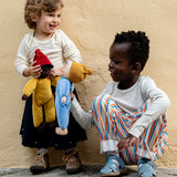 Child playing with Kathe Kruse Saffron nana waldorf doll with another child holding a cloud waldorf doll