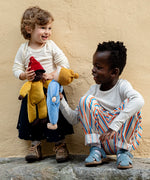 Child playing with Kathe Kruse Saffron nana waldorf doll with another child holding a cloud waldorf doll