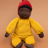 Kathe Kruse Saffron nana waldorf doll sitting against a burnt orange background.