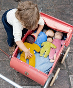 Child playing with Kathe Kruse nana Saffron waldorf doll with other waldorf dolls in a pram