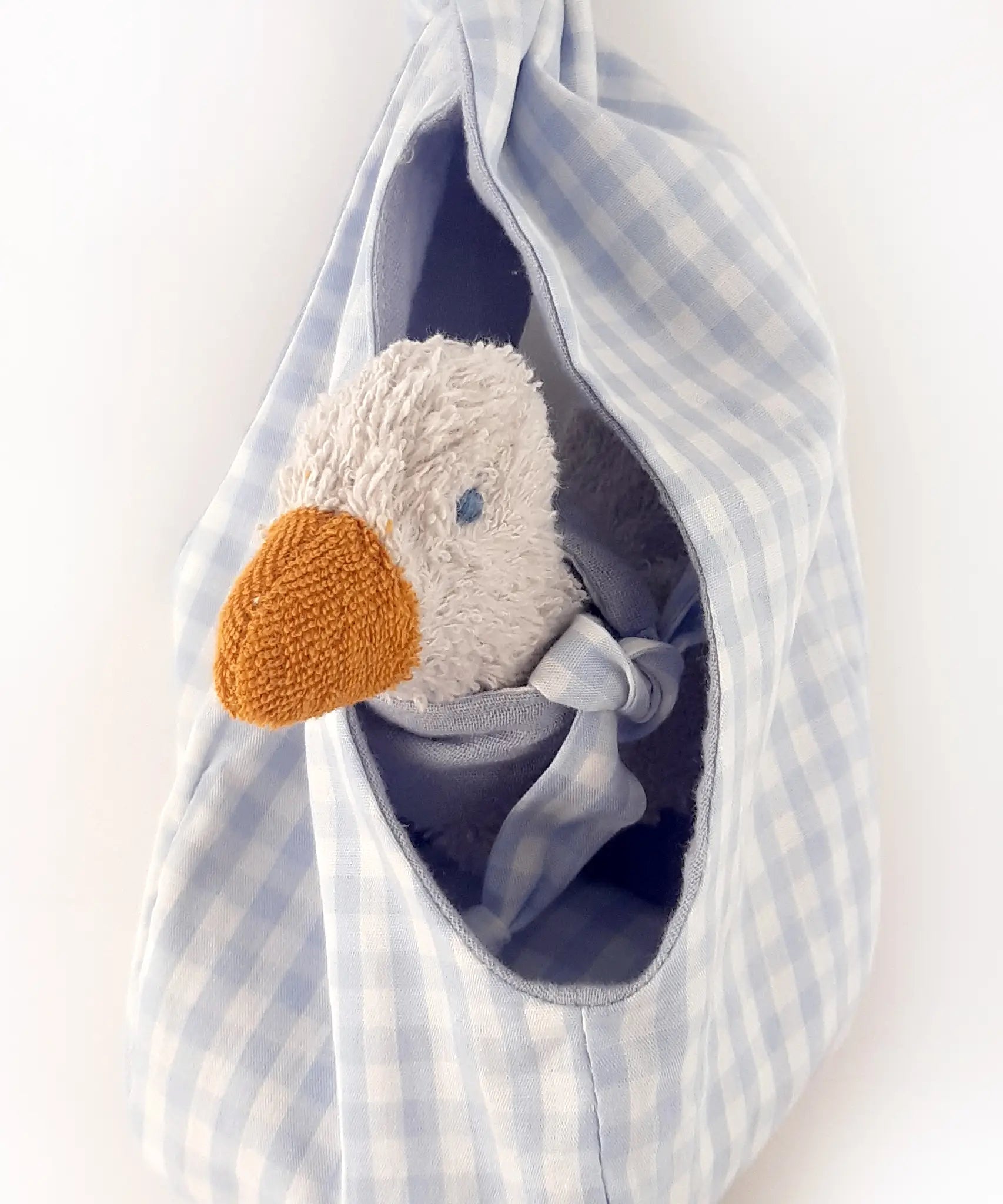 A white duckling soft toy sitting inside a blue gingham fabric nest from the Kathe Kruse animal music box set