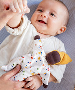 Käthe Kruse Waldorf Doll Nini Sunshine placed in the crook of a baby's arm.