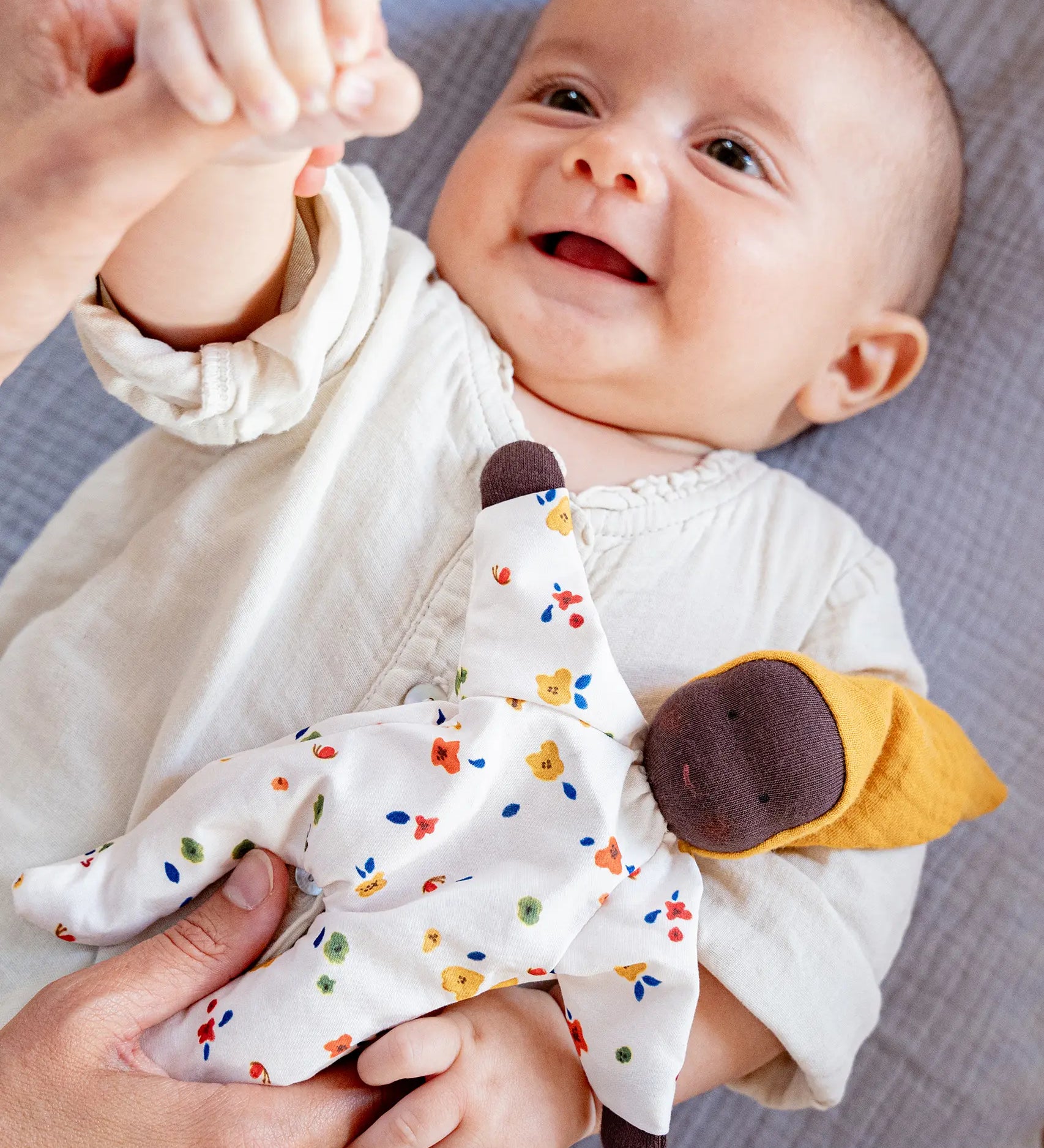 Käthe Kruse Waldorf Doll Nini Sunshine placed in the crook of a baby's arm.