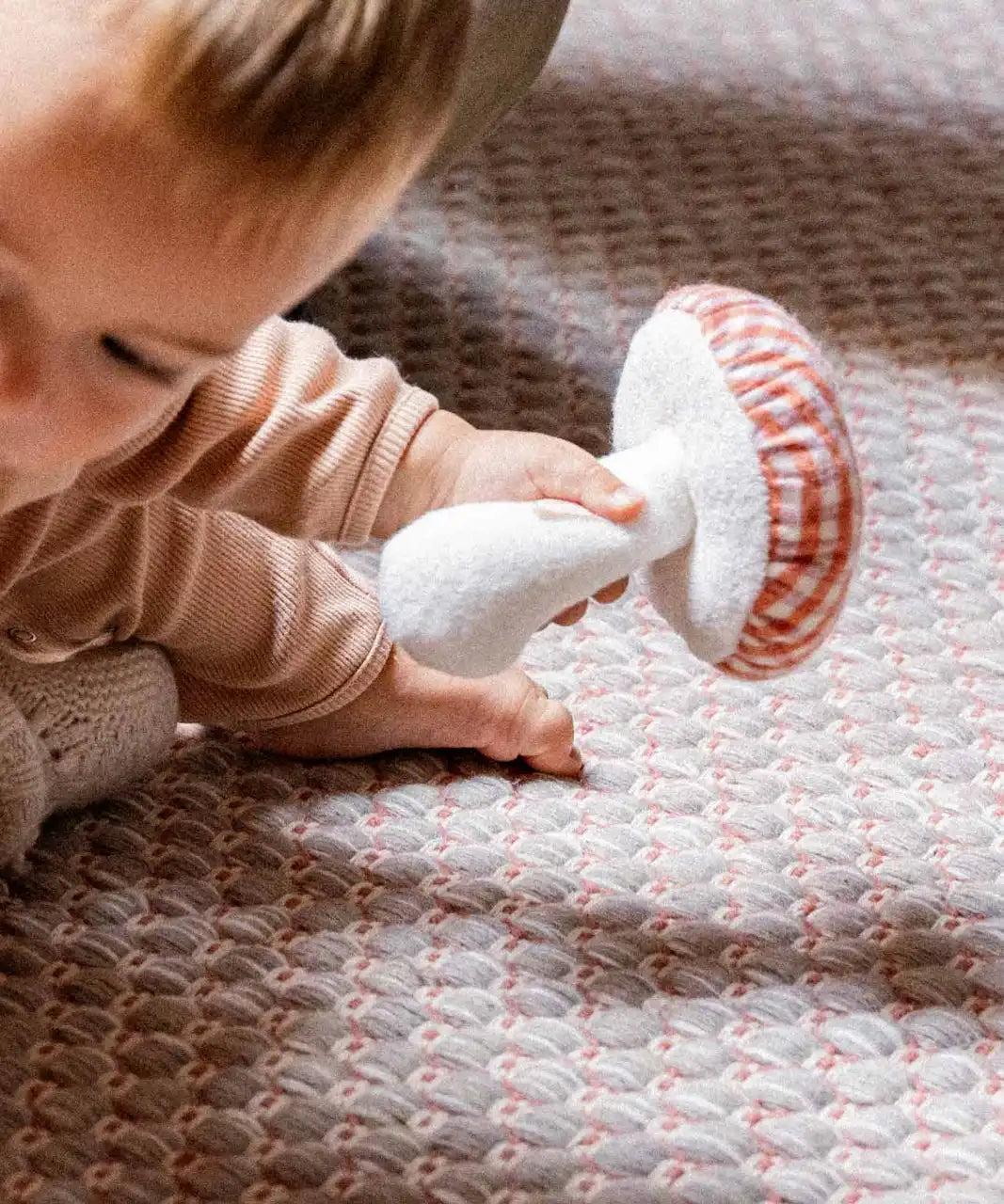 Käthe Kruse baby pilz grabbing toy, a red and white gingham topped toadstool shaped soft toy. 