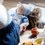 Käthe Kruse Waldorf doll Tilda placed on a patterned pillow with the little white bird on her hand.