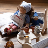 Käthe Kruse Waldorf doll Tilda placed in a wooden seat next to a smaller blue doll. 