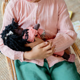 Käthe Kruse Waldorf Doll Nia cradled in a child's arms. Cotton doll filled with sheep's wool.