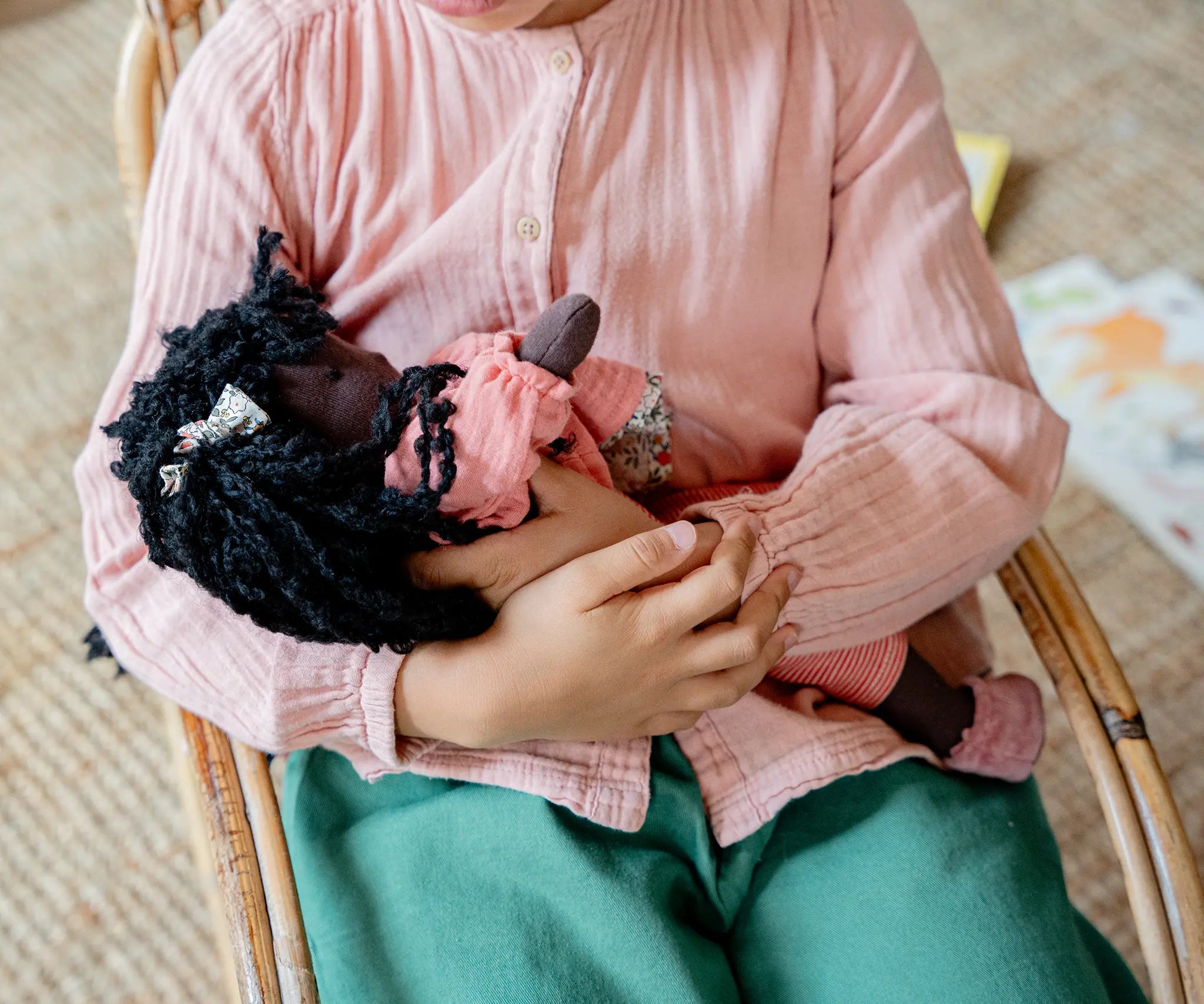 Käthe Kruse Waldorf Doll Nia cradled in a child's arms. Cotton doll filled with sheep's wool.