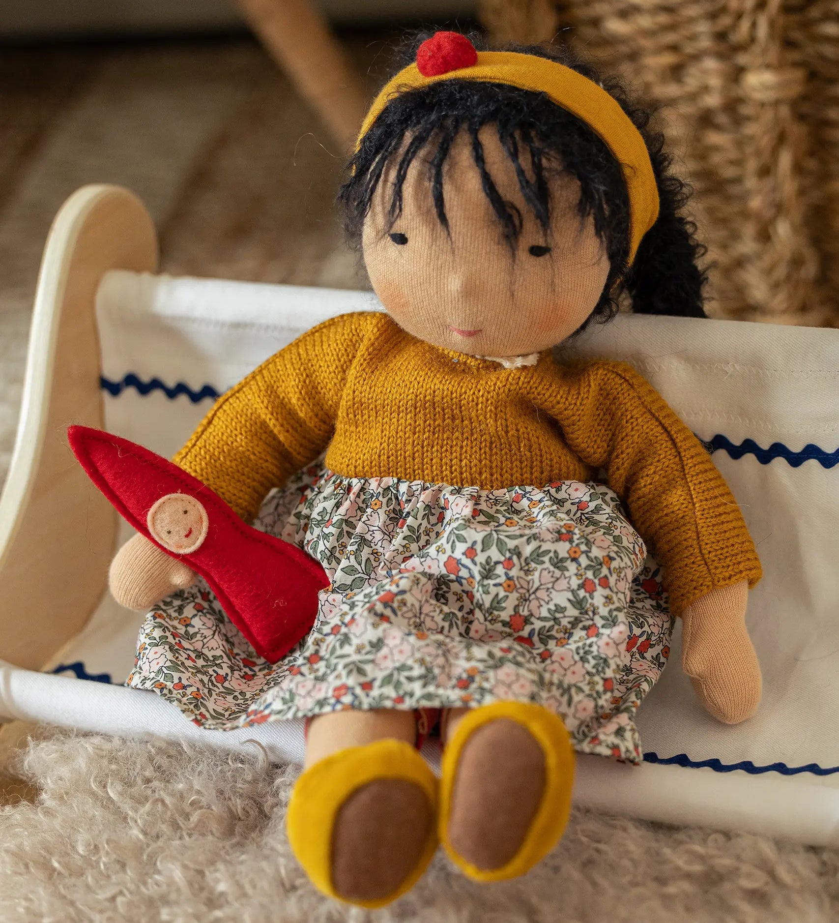 Käthe Kruse Waldorf Doll Kiki in a sitting position with a little red felt gnome.
