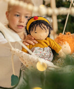 Käthe Kruse Waldorf Doll Kiki being placed in a doll hammock by a child.