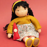 Käthe Kruse Waldorf Doll Kiki in a seated position with the ref felt gnome placed in the crook of her arm.