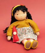 Käthe Kruse Waldorf Doll Kiki in a seated position with the ref felt gnome placed in the crook of her arm.