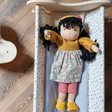 Käthe Kruse Waldorf Doll Kiki placed in a wooden doll's cot.