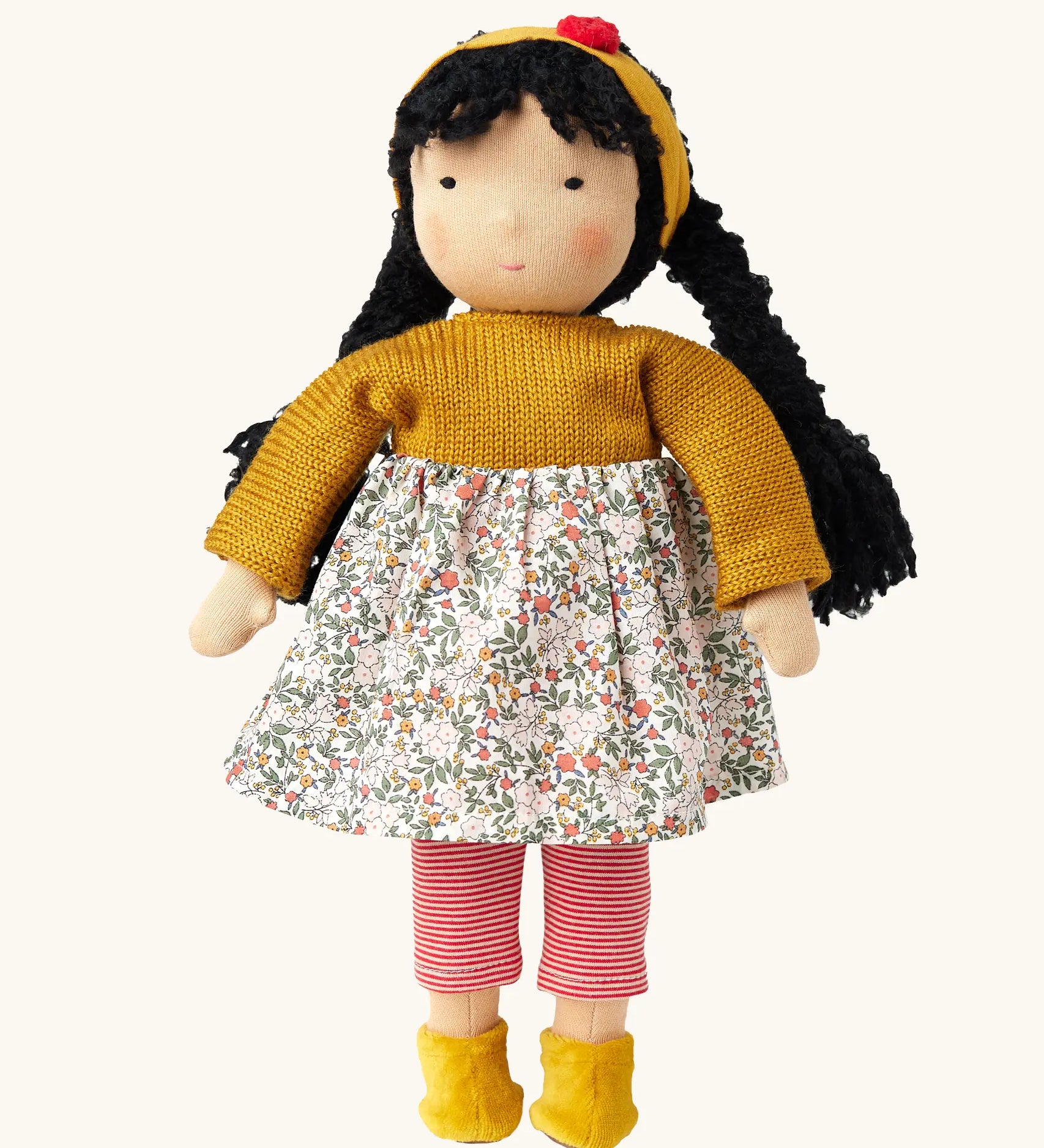 Käthe Kruse Waldorf Doll Kiki, white skin, black hair, ocre yellow headband, knitted jumper and boots, floral print skirt and red and white striped leggings.