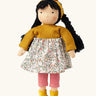 Käthe Kruse Waldorf Doll Kiki, white skin, black hair, ocre yellow headband, knitted jumper and boots, floral print skirt and red and white striped leggings.