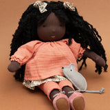 Käthe Kruse Waldorf Doll Nia in a sitting position with the small grey felt mouse that it comes with placed on her lap.