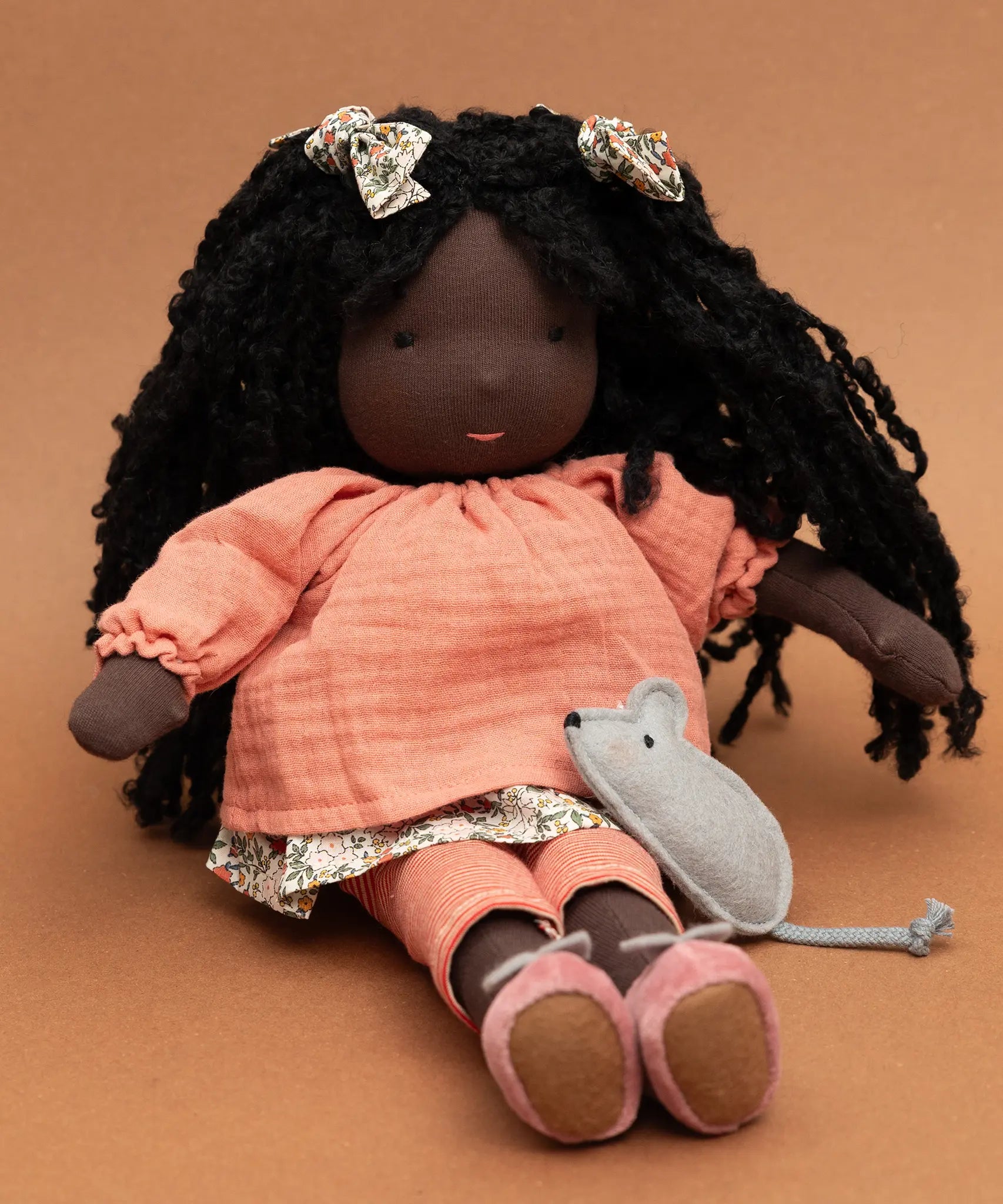 Käthe Kruse Waldorf Doll Nia in a sitting position with the small grey felt mouse that it comes with placed on her lap.