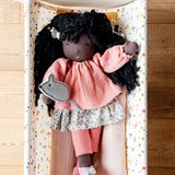 Käthe Kruse Waldorf Doll Nia placed in a doll's crib with the felt mouse on her hand.
