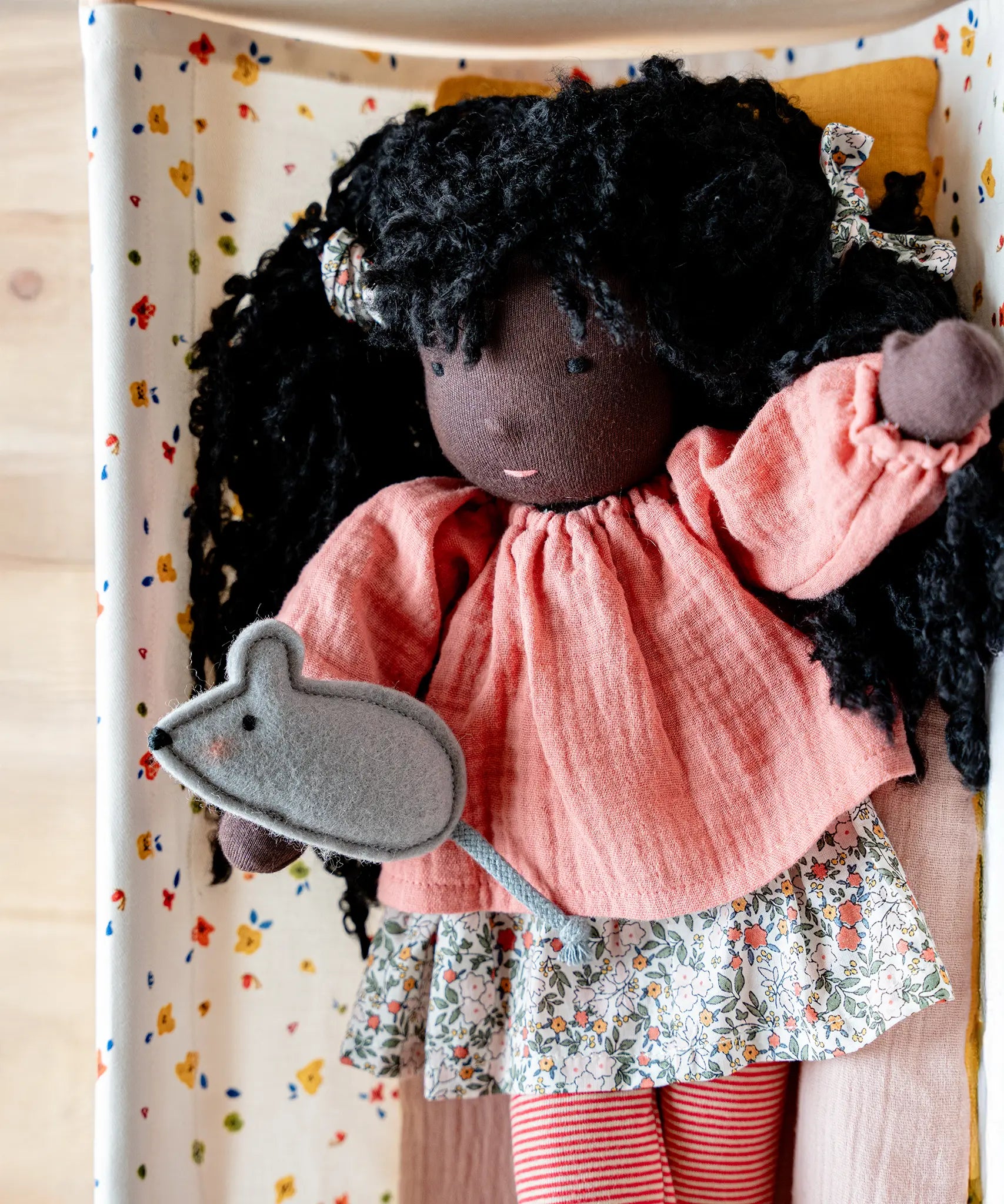 Käthe Kruse Waldorf Doll Nia placed in a doll's crib with small grey felt mouse that comes with it. 