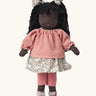  Käthe Kruse Waldorf Doll Nia with long black hair and black skin. Pink knitted jumper, floral print skirt with matching hair bows, red and white stripe leggings and pink booties with white bows.