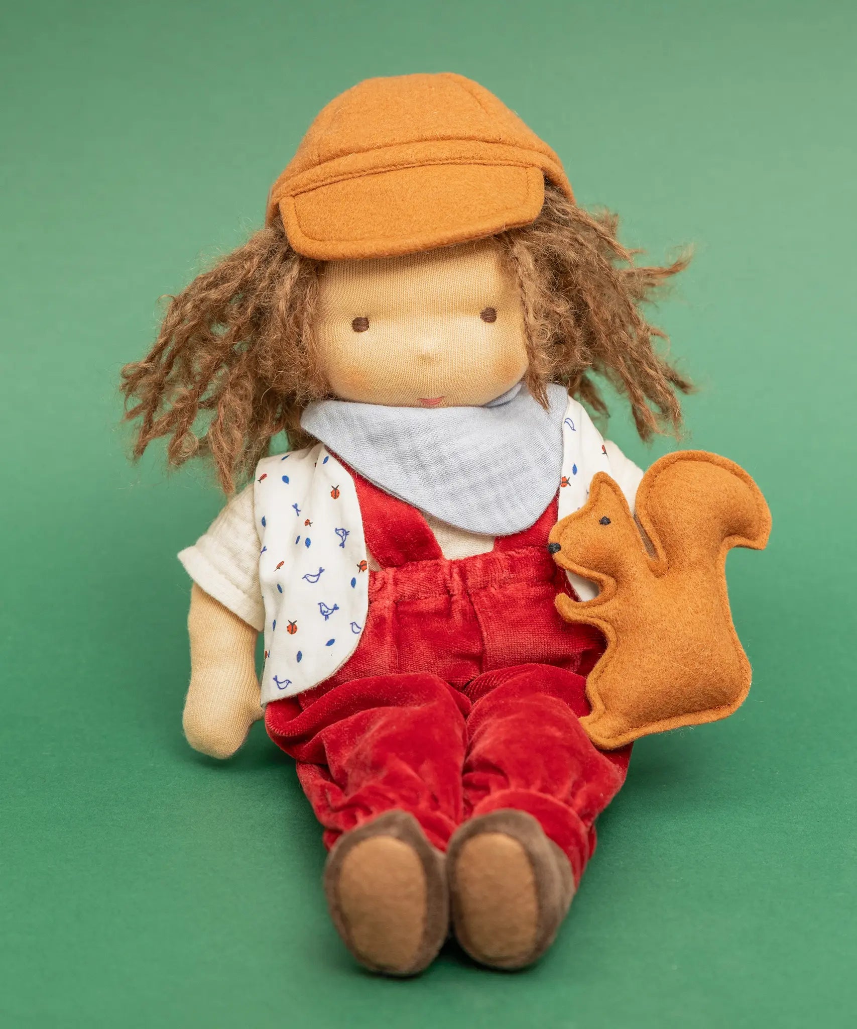 Käthe Kruse Waldorf doll Toni in a sitting position with a small felt squirrel on it's lap. 