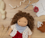 Käthe Kruse Waldorf doll Toni with it's hat taken off and materials from making process around it.