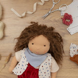 Käthe Kruse Waldorf doll Toni with it's hat taken off and materials from making process around it.